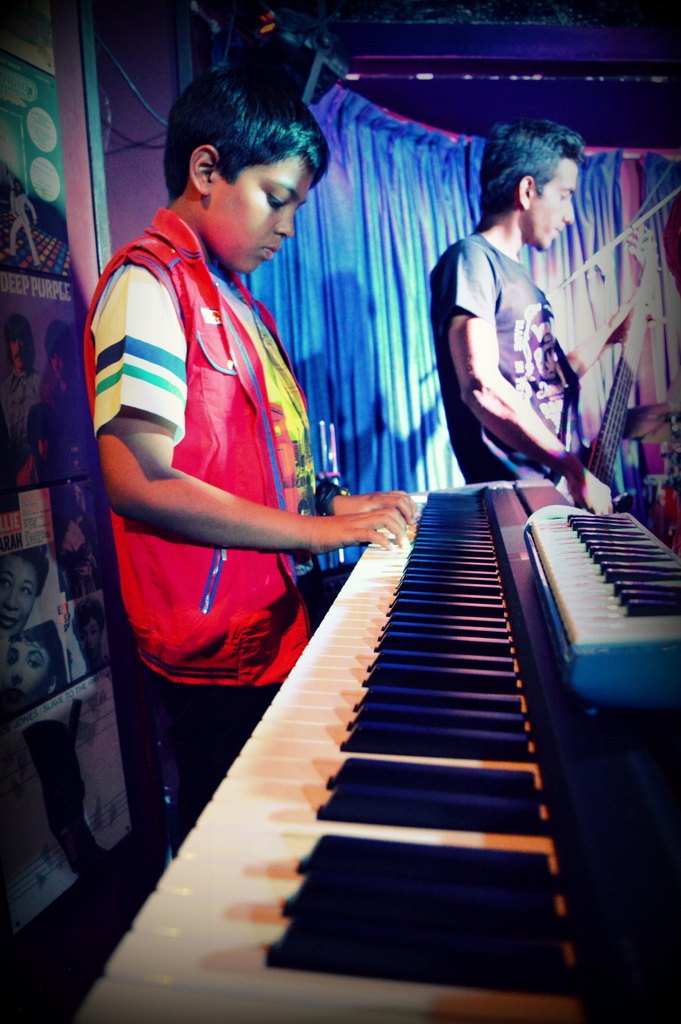 Young student in red vest at the keyboard, with band