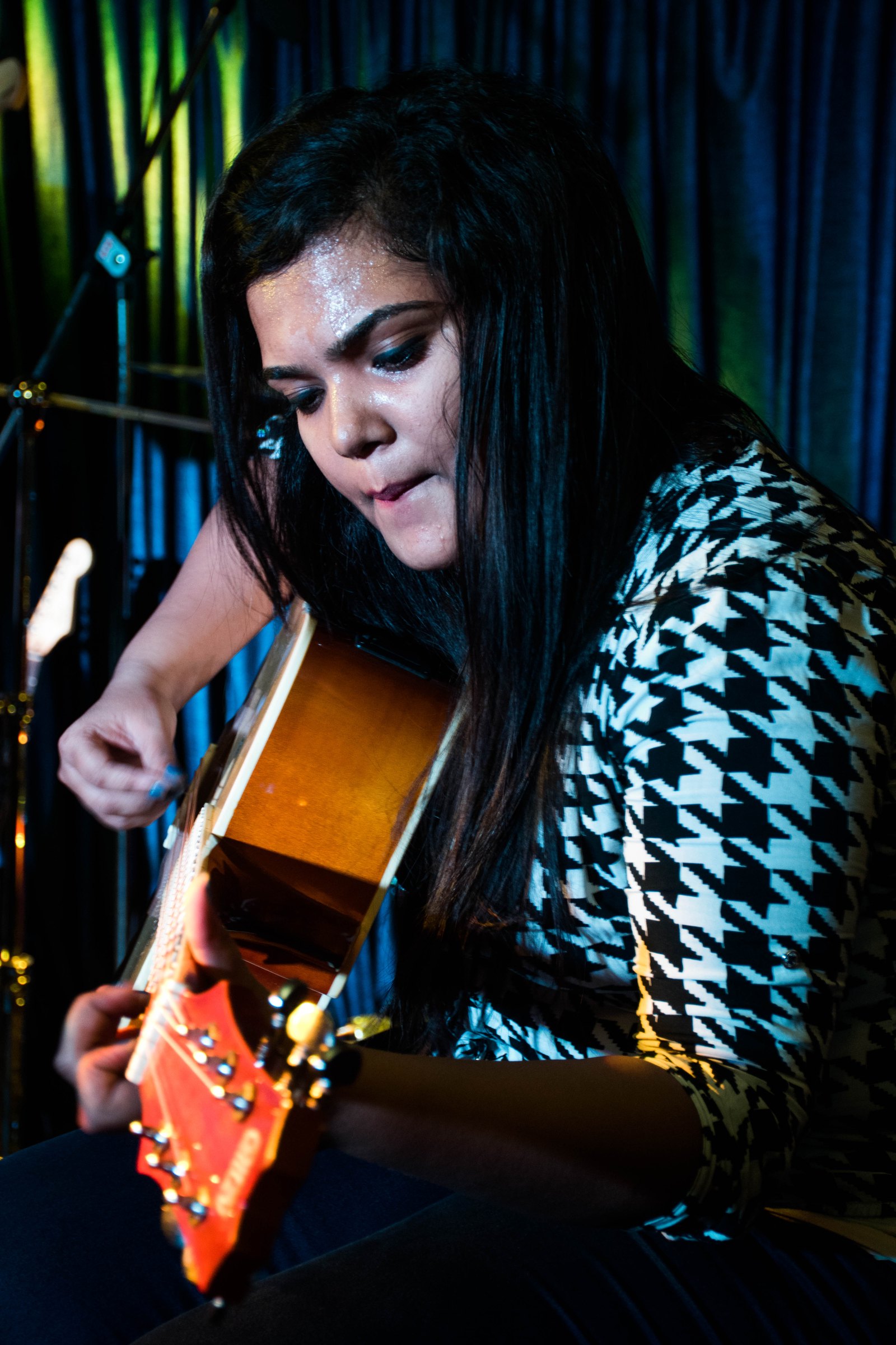 Woman playing acoustic with houndstooth top