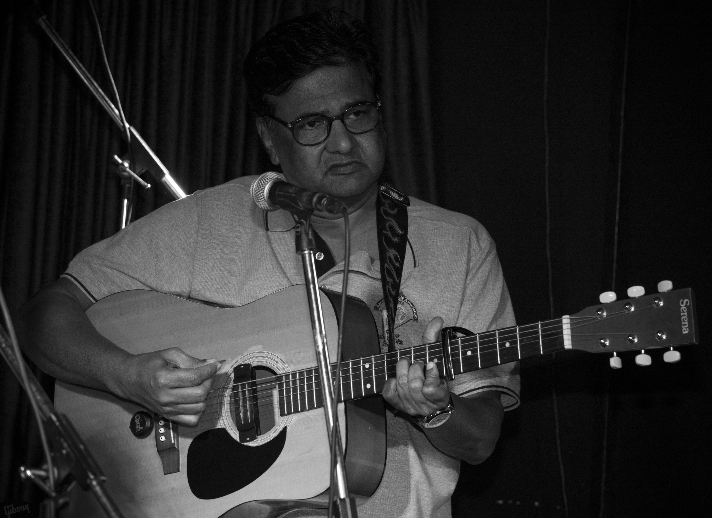 Mature guitarist with acoustic and mic, B&W